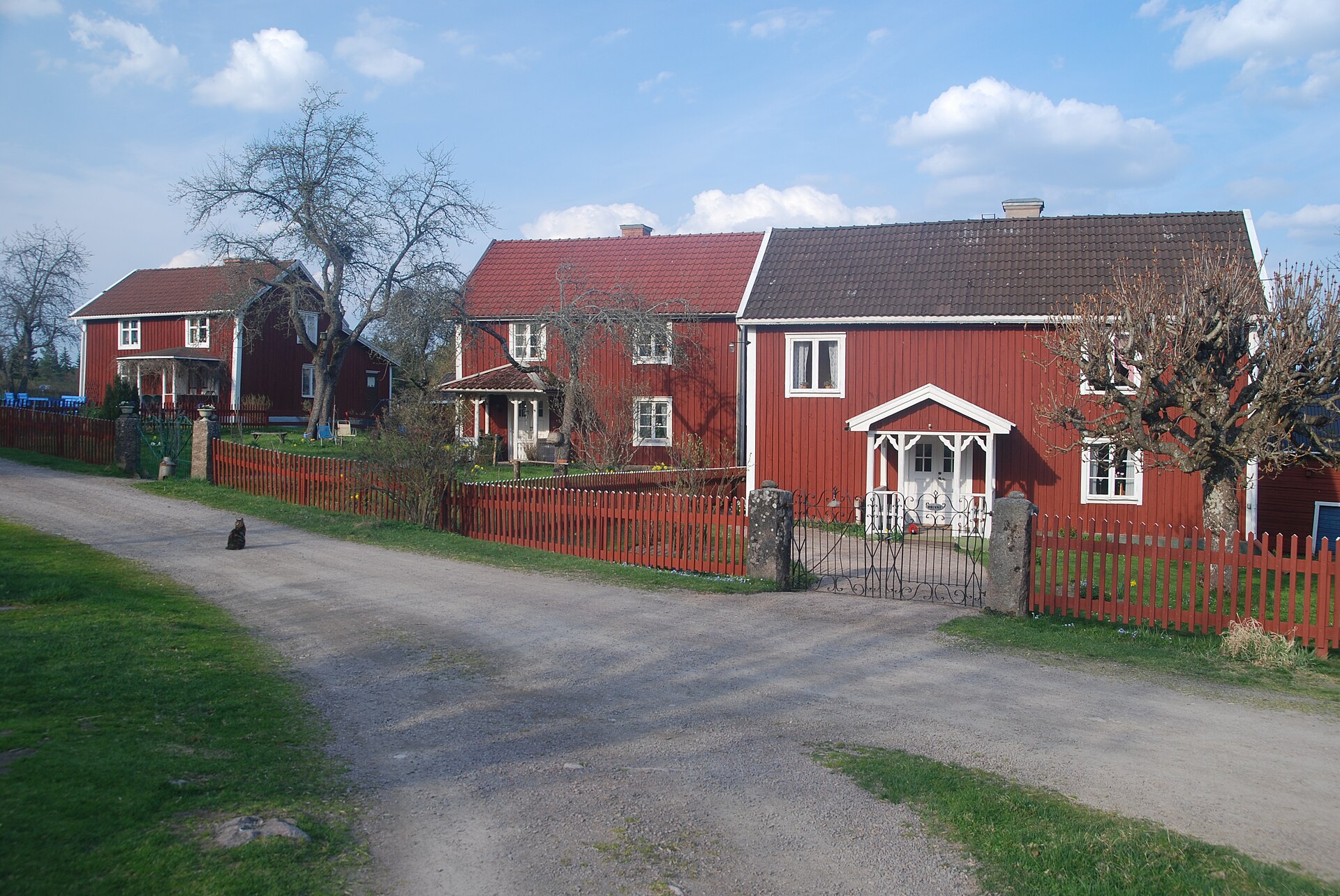 Bullerbü in Småland: die drei roten Höfe von Sevedstorp mit weißen Ecken und rotem Lattenzaun an einem Schotterweg