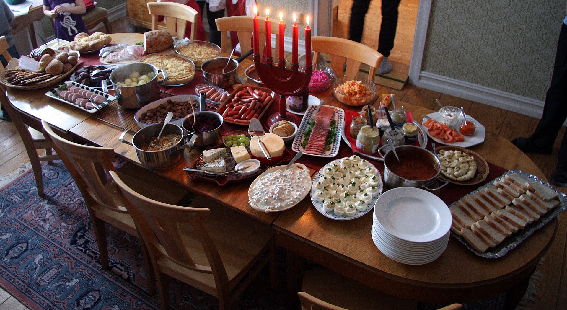 Julbord: privates schwedisches Weihnachtsbuffet mit Adventsleuchter auf dem Esstisch