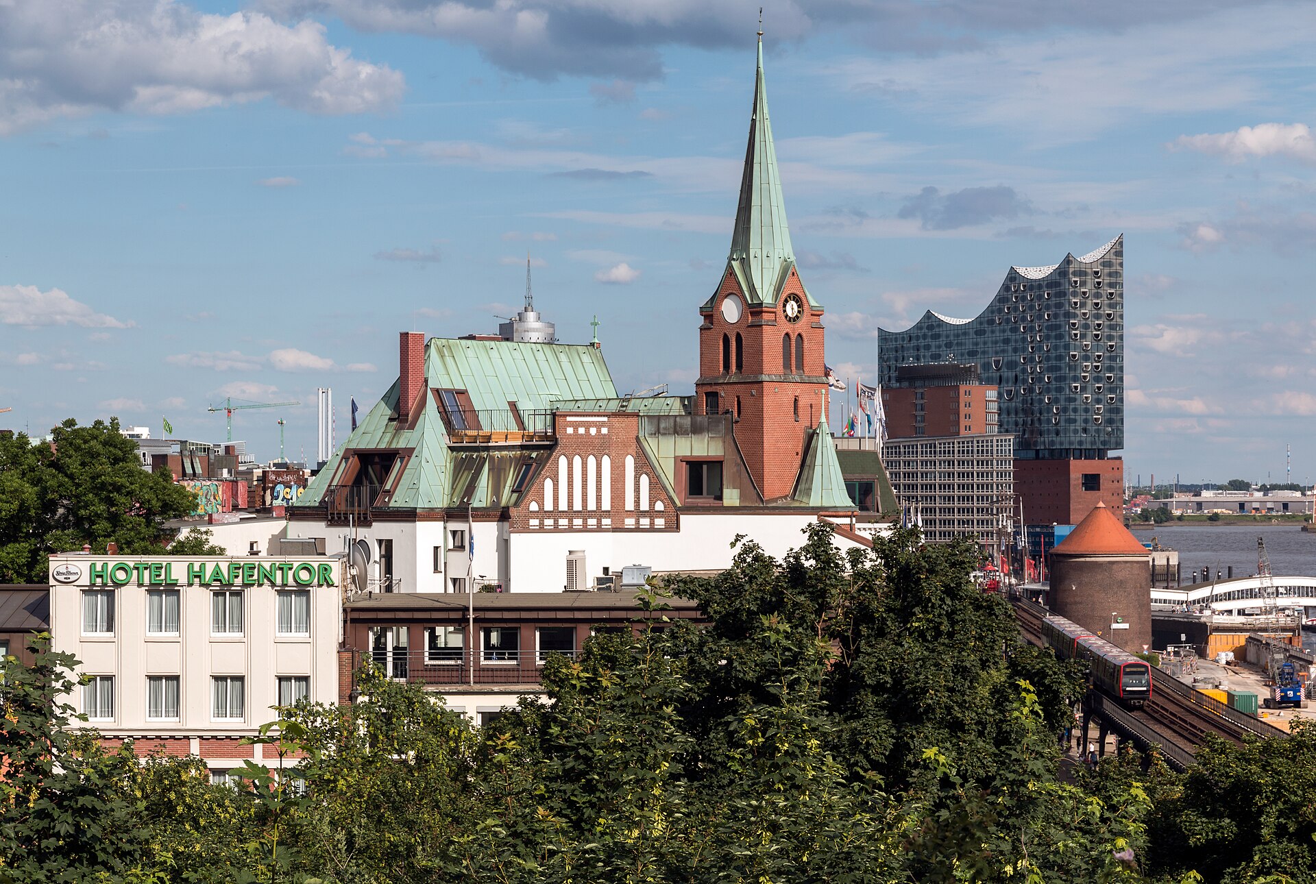 Schwedische Gustaf-Adolfs-Kirche in Hamburg mit grünem Kupferturm, dahinter die Elbphilharmonie