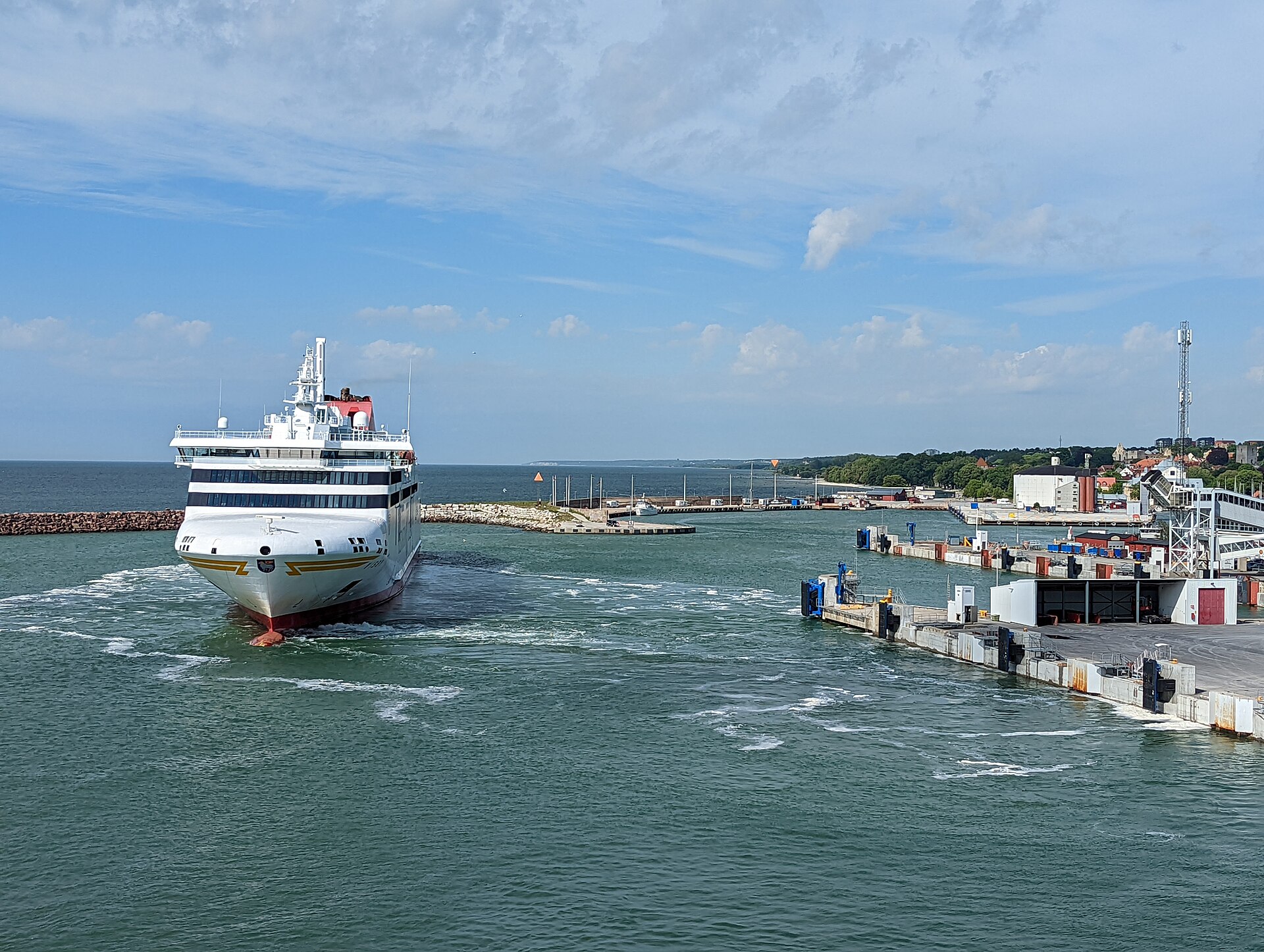 Die weiße Gotlandfähre M/S Visby fährt aus dem Hafen von Visby, rechts die Kaianlagen, im Hintergrund die Ostsee