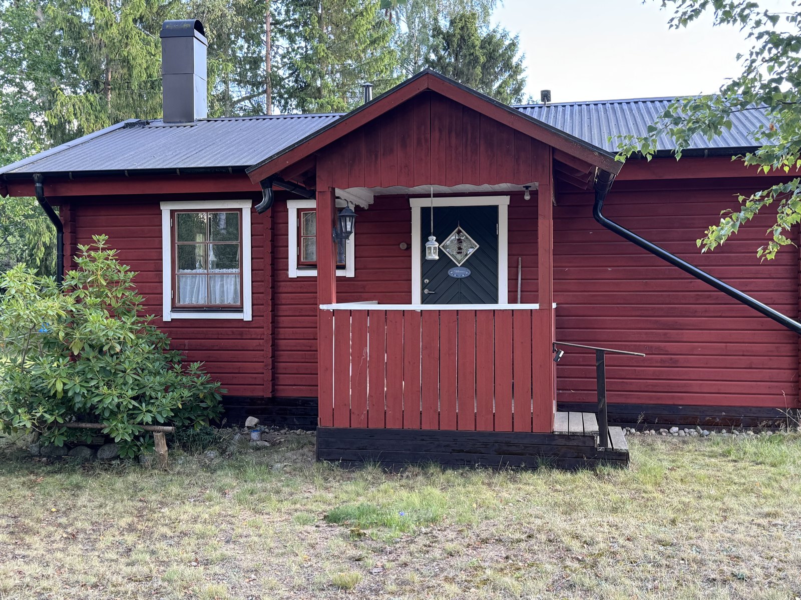 Rotes Holzhaus mit Veranda und weißen Fensterrahmen im Sommer in Blekinge, Schweden