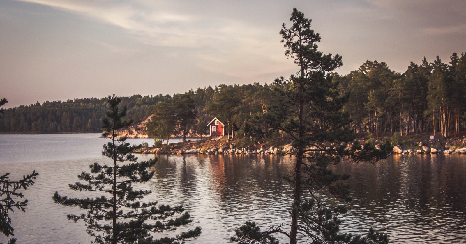 Regionen in Schweden: rotes Holzhaus an einem See im Abendlicht