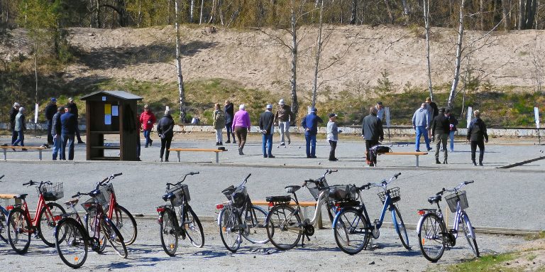 Als Rentner nach Schweden: Rentnerinnen und Rentner spielen Boule auf einer Kiesfläche in Ystads Sandskog, im Vordergrund eine Reihe Fahrräder mit Körben