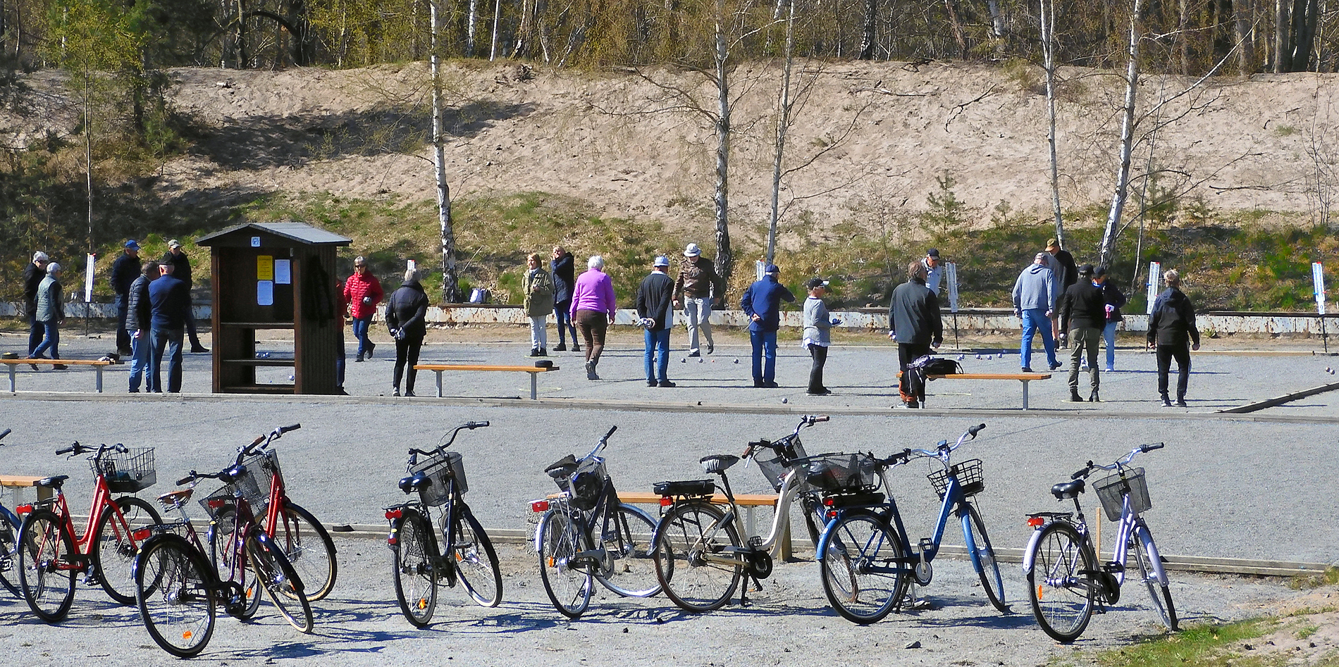 Als Rentner nach Schweden: Rentnerinnen und Rentner spielen Boule auf einer Kiesfläche in Ystads Sandskog, im Vordergrund eine Reihe Fahrräder mit Körben