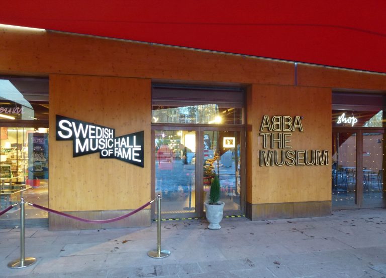 Eingang von ABBA The Museum auf Djurgården in Stockholm mit Leuchtschrift an der Holzfassade