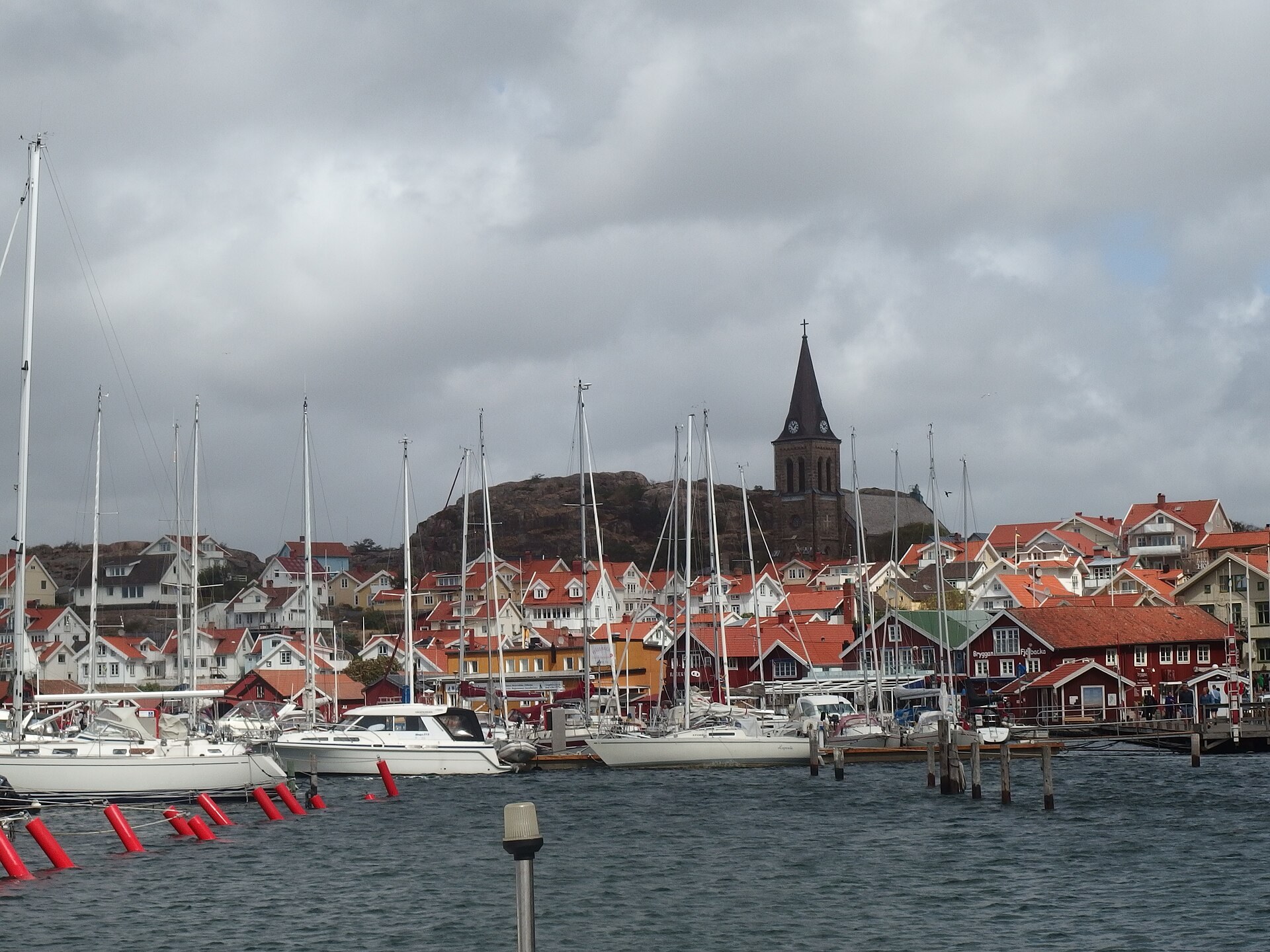 Hafen von Fjällbacka mit Segelbooten, bunten Häusern, Kirchturm und dem Felsen Vetteberget