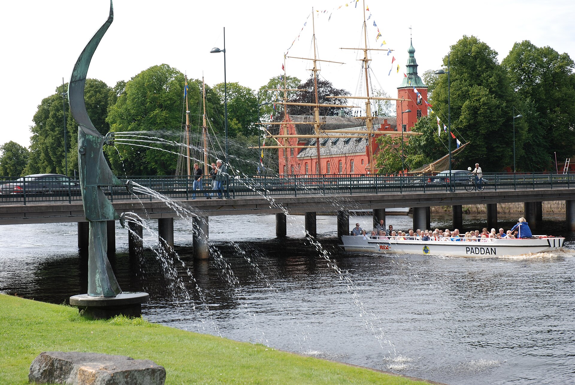 Skulptur am Fluss Nissan in Halmstad mit rotem Schloss und Segelschiff im Hintergrund