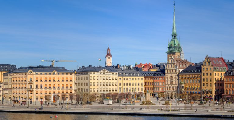 Altstadt Gamla stan in Stockholm vom Wasser aus mit bunten Fassaden und grünem Kirchturm