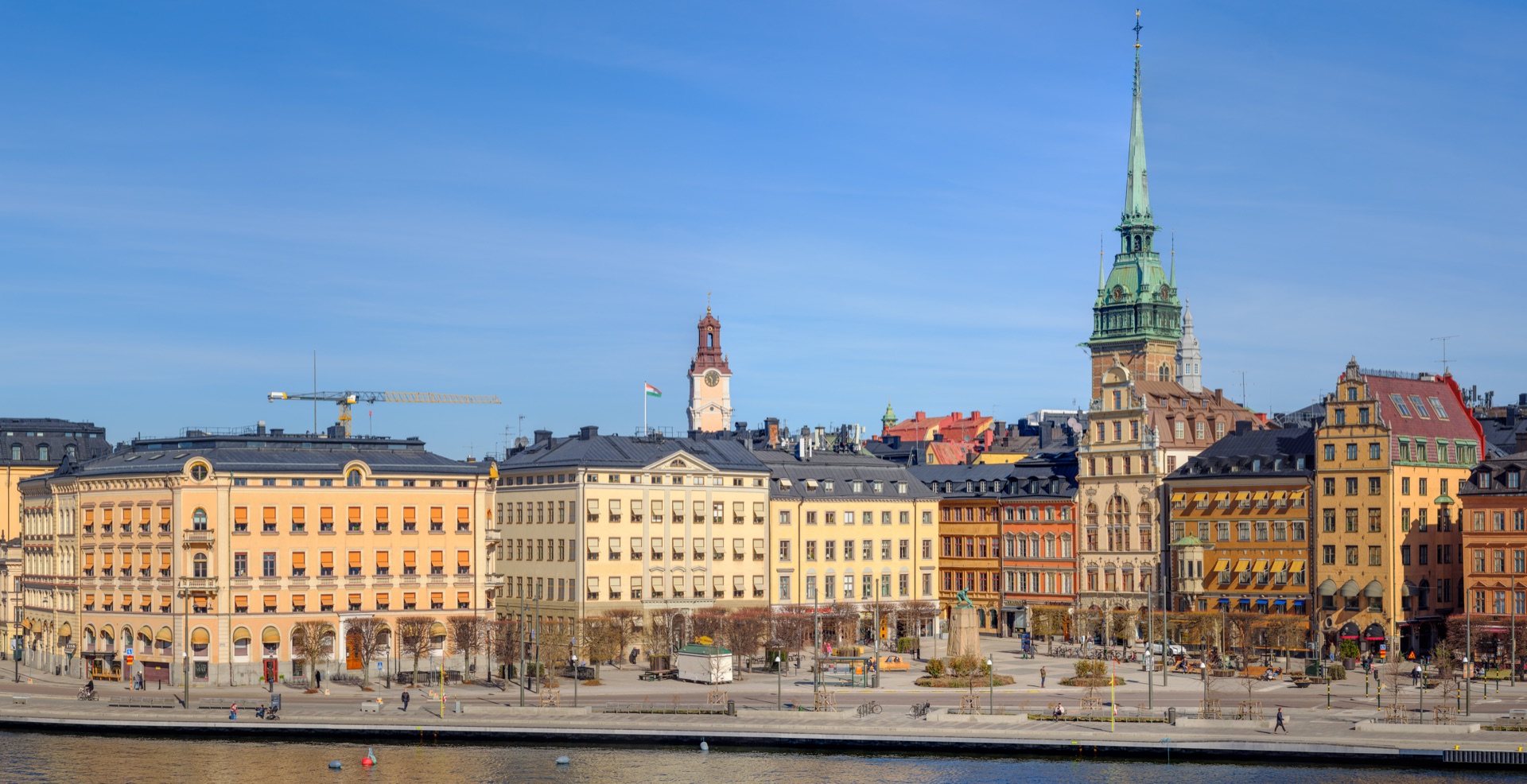 Altstadt Gamla stan in Stockholm vom Wasser aus mit bunten Fassaden und grünem Kirchturm