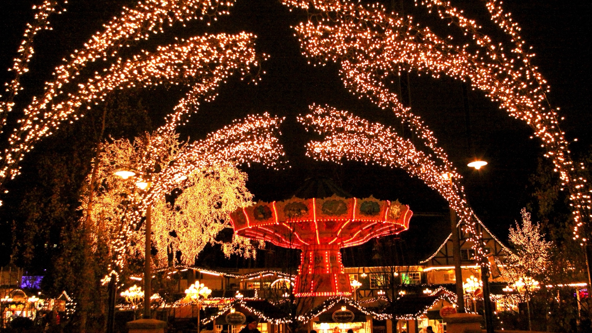 Weihnachtsbeleuchtung im Freizeitpark Liseberg in Göteborg mit Lichterbögen über dem Kettenkarussell