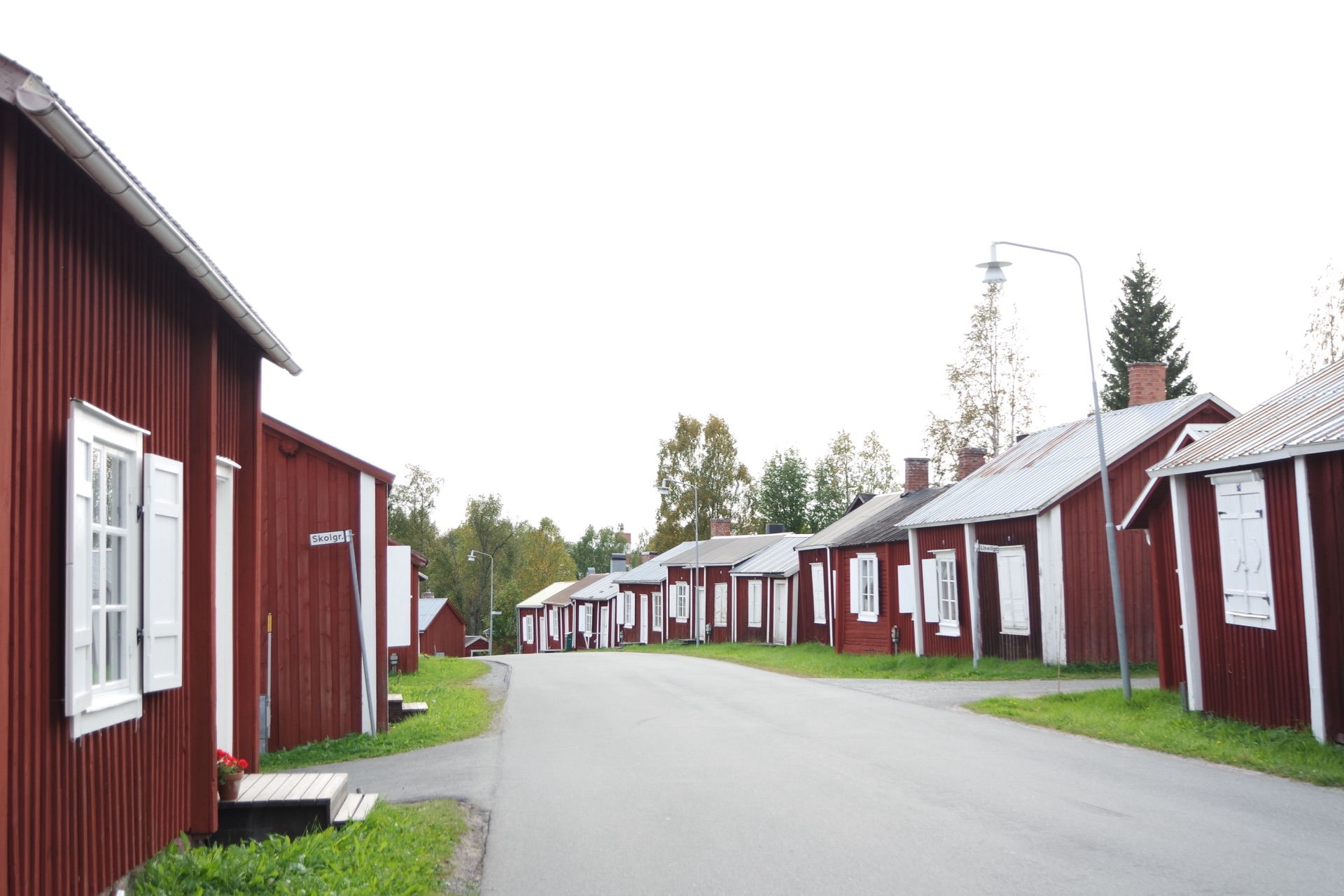 Rote Holzhäuser der Kirchstadt Gammelstad bei Luleå an einer ruhigen Straße