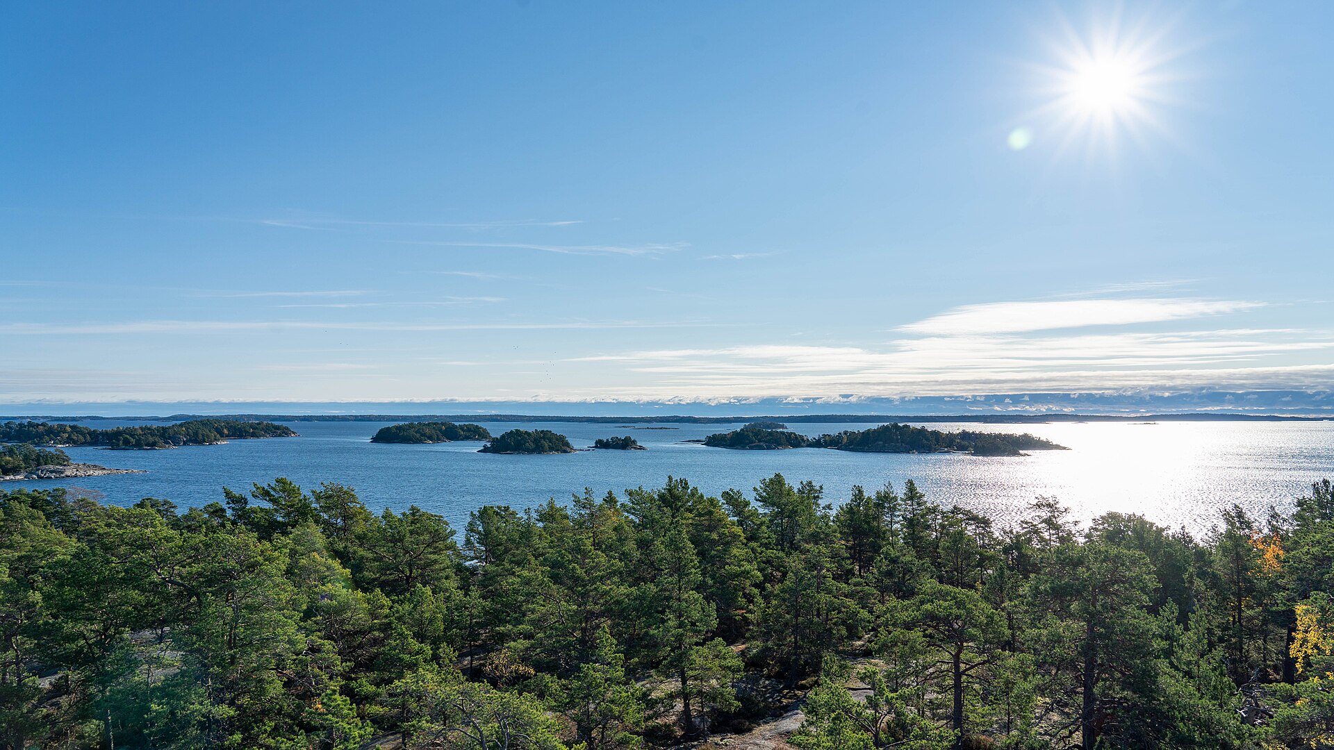 Kleine bewaldete Inseln im Stockholmer Schärengarten unter blauem Himmel
