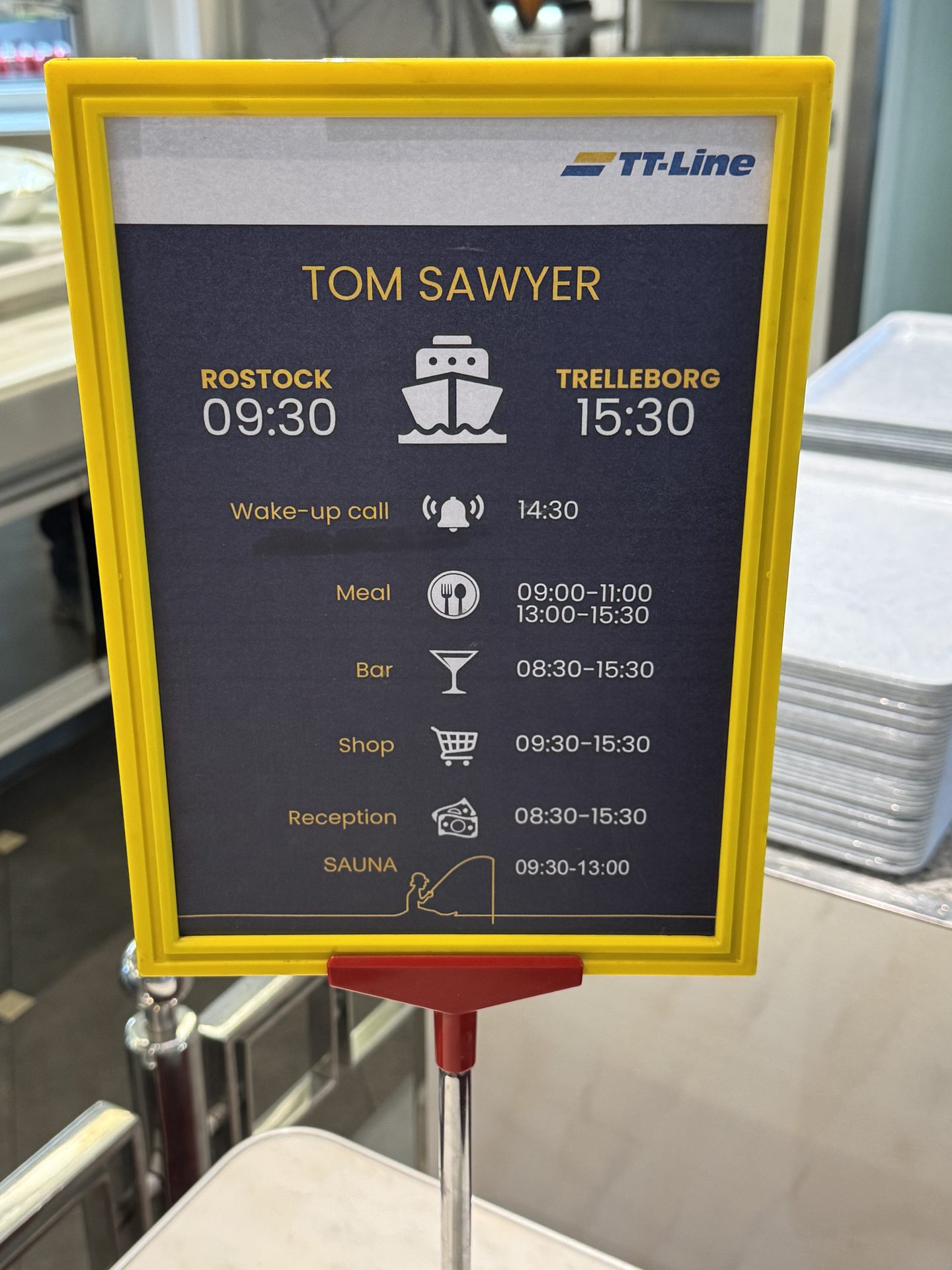 Infotafel an Bord der Tom Sawyer: Rostock 9:30, Trelleborg 15:30, Weckruf 14:30, Essen, Bar, Shop, Rezeption und Sauna mit Öffnungszeiten