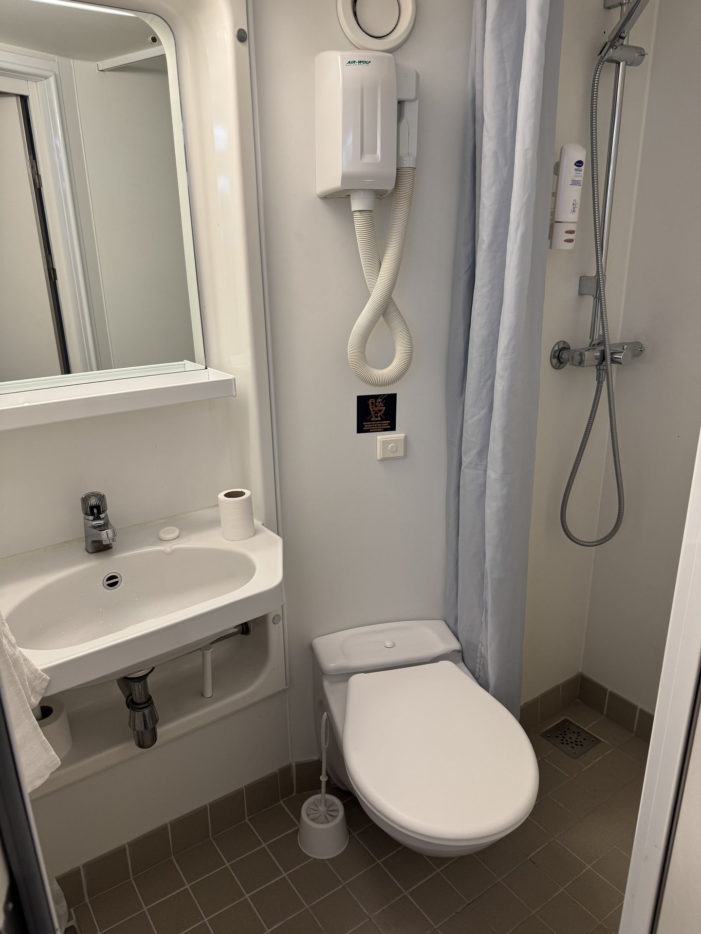 Bad einer Kabine auf der Tom Sawyer mit Waschbecken, WC, Dusche mit Vorhang und Föhn an der Wand