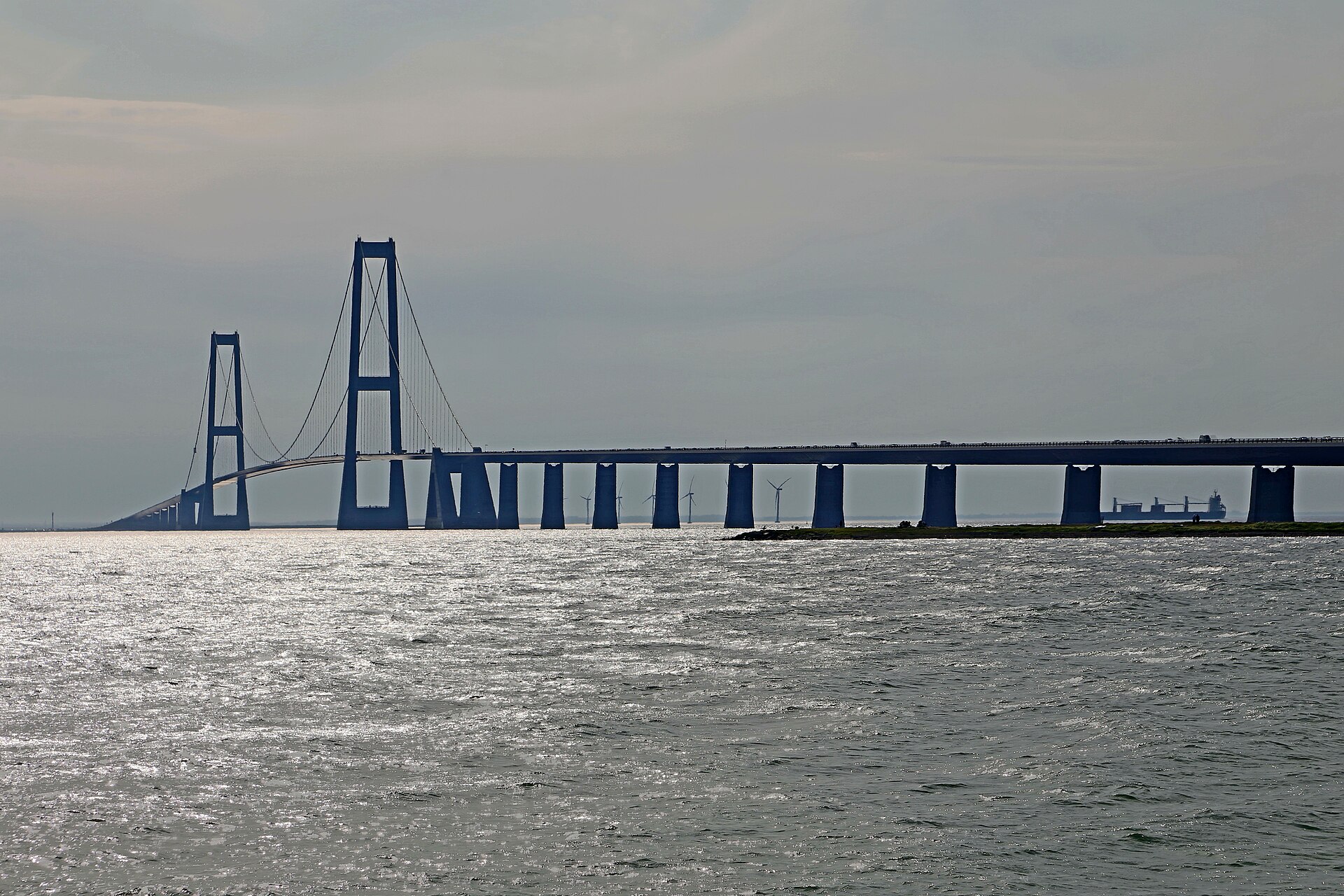 Die Storebæltsbrücke über den Großen Belt auf dem Weg über Dänemark nach Schweden, hinter den Pfeilern Windräder und ein Frachtschiff
