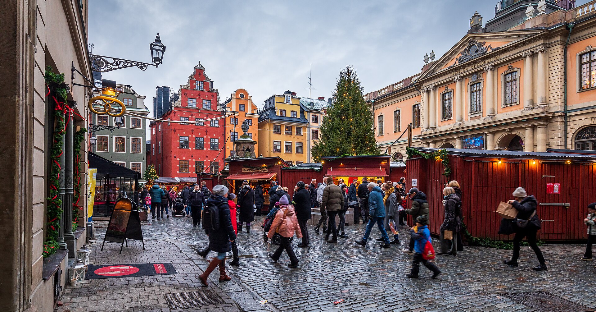 Weihnachtsmarkt Stockholm: rote Marktbuden, geschmückter Weihnachtsbaum und bunte Giebelhäuser auf dem Stortorget in Gamla stan im Dezember